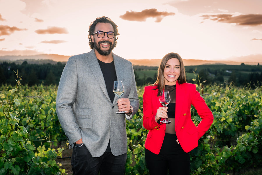Dr. Volinder Dhesi and Dr. Alexandria Russ, co-founders of Stained Tooth, holding glasses of wine in a vineyard